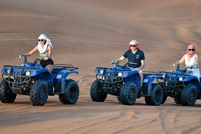 Three young travelers riding quad bikes on the desert sand