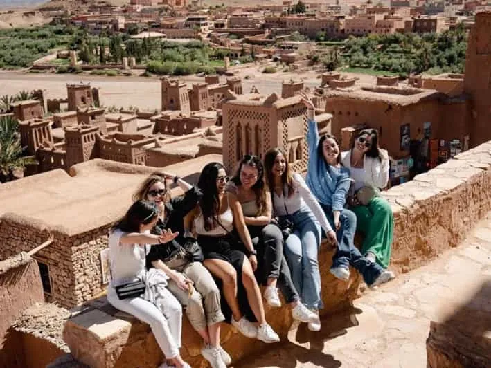 Students sitting on a wall overlooking the ksar of Ait Ben Haddou